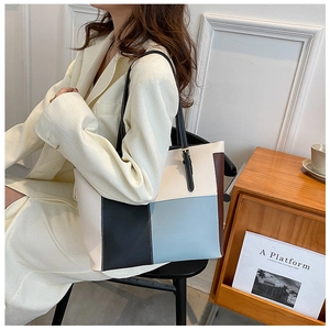 Detail of color-block tote bag featuring adjustable golden buckle and contrast stitching