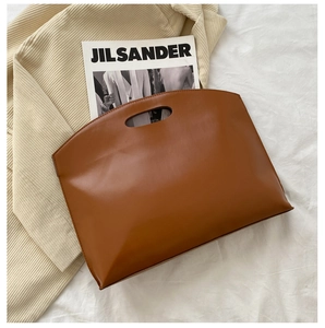 Detailed top view of minimalist brown leather tote bag with unique cut-out handles