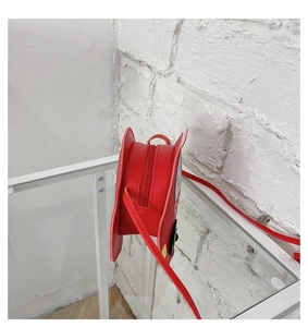 Détail du sac à bandoulière rond rouge avec fermeture éclair et sangle en cuir PU
