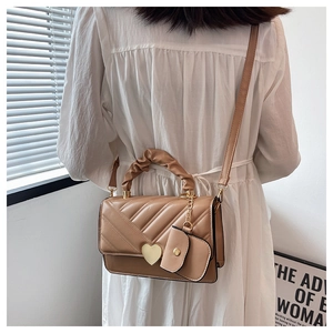 Detail of khaki PU leather bag with heart-shaped gold lock and V-quilted texture