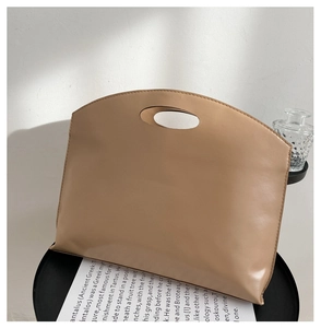 Close-up of beige minimalist tote bag with integrated oval cut-out handle on metal table