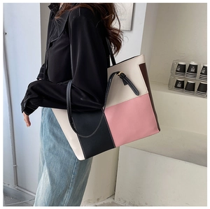 Detail of color-block tote bag showing premium PU leather texture and black slim handles