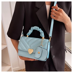 Light blue quilted handbag featuring a gold heart lock and ruffled handle on a black blazer