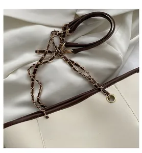 Close-up of leather and gold chain shoulder strap on a beige contrast tote bag