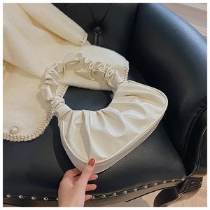 Detail der cremeweißen Cloud Bag mit geraffter PU-Lederstruktur auf einem Ledersofa