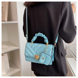 Detail of light blue V-quilted leather bag with golden heart clasp and mini coin purse