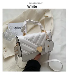 Close-up of white quilted handbag with golden heart clasp and detachable mini coin purse