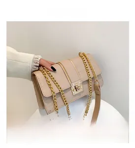 Detailed close-up of beige crocodile texture bag with gold chain and wide strap