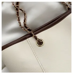 Detail of light gold chain strap with brown leather and quality hardware on beige tote bag