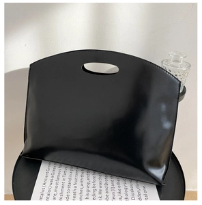 Detailed view of large black glossy leather tote bag with unique cutout handle design