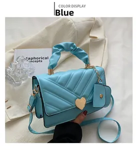 Close-up of light blue pleated handbag with gold heart clasp and mini coin purse