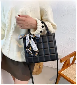 Gros plan d'un sac à main noir carré avec texture 3D diamant et foulard décoratif