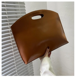 Close-up of minimalist brown oil leather handbag featuring modern cutout oval handles