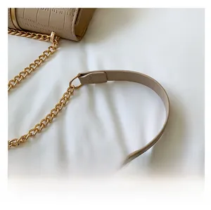 Close-up of beige crocodile texture leather bag featuring gold chain shoulder strap