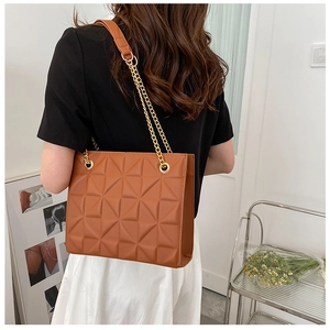 Vue détaillée d'un sac à bandoulière matelassé caramel avec chaîne dorée sur un mannequin