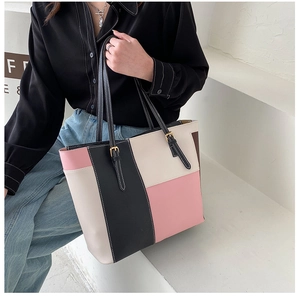 Close-up of color-block tote bag with adjustable leather handles and gold buckles