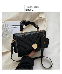 Detail of black quilted PU leather handbag with heart-shaped gold lock and V-stitch pattern