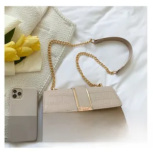 Detail shot of beige crocodile pattern texture and gold chain strap on the square bag