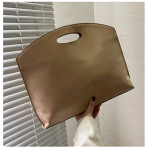 Detail view of smooth cream faux leather briefcase with unique circular cutout handle