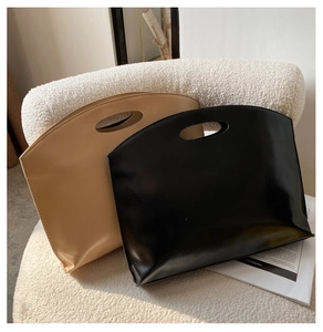 Minimalist beige and black smooth leather tote bags resting on a cozy cream textured sofa