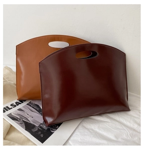Close-up of minimalist half-round leather handbags in deep reddish brown and camel