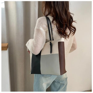 Detailed back view of a color-block tote bag with adjustable black straps on a model