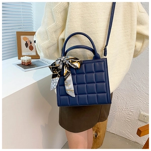 Détail du sac à main matelassé bleu foncé avec foulard en soie et texture en simili