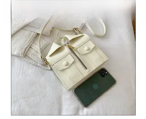 Close-up of cream shirt-style crossbody bag showing creative pocket and zipper details
