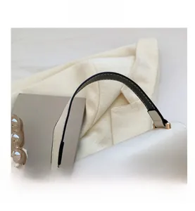 Macro detail of comfortable white leather handbag handle with gold hardware and stitching