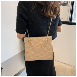 Détails de la texture matelassée géométrique et chaîne dorée sur sac beige