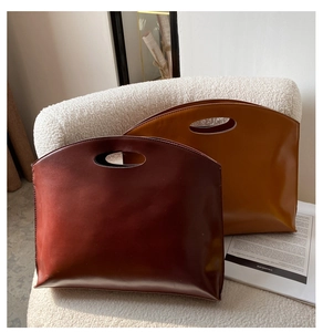 Close-up of minimalist oil leather handbags in dark brown and mustard on soft fleece