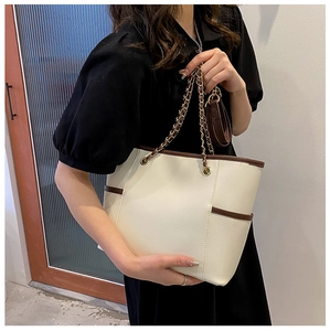 Side view of white and brown tote bag with metal chain strap and mini coin purse