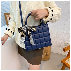Détail d'un sac à main matelassé bleu marine avec un nœud en soie à motif géométrique