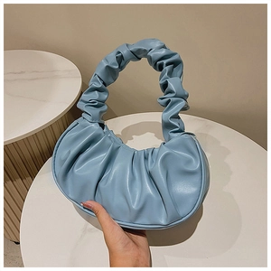 Nahaufnahme der hellblauen Wolken-Handtasche mit gerafftem Griff auf einem Marmortisch