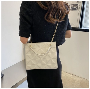 Gros plan sur le sac cabas crème matelassé avec chaîne dorée et texture géométrique