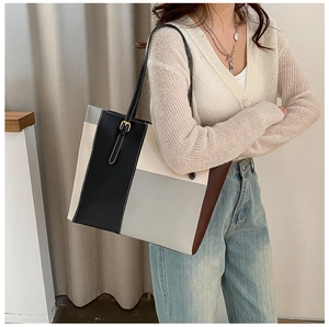 Detail of color-block tote bag with geometric design shown on model for size perspective