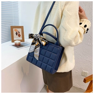 Détail d'un sac à main bleu marine matelassé avec un foulard en soie décoratif