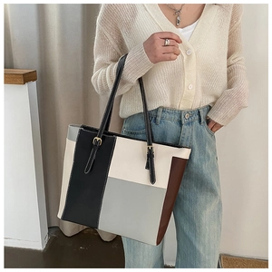 Detailed close-up of color-block tote bag stitching and golden metal buckle hardware