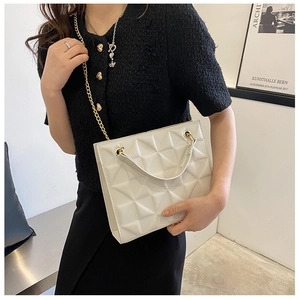 Détail du sac matelassé blanc en cuir avec chaîne dorée et texture pyramide en relief