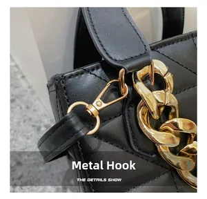 Detailed macro view of golden metal hooks and chain on a black quilted leather bag