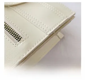 Detail of cream leather handbag showing precise stitching and premium gold metal zipper