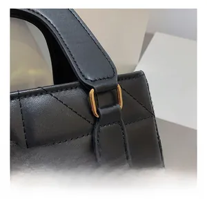 Detail showing high-quality stitching and gold square buckle on a black quilted handbag