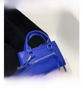 Detail of bright blue textured leather handbag with decorative zipper and fringe accents