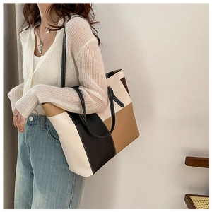 Detail of a large color-block tote bag in beige, black, and brown with slim straps