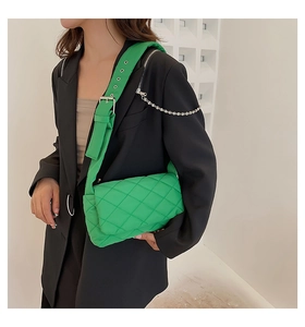 Détail du sac en nylon matelassé vert vif avec bandoulière à œillets et chaîne argentée