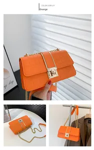 Detail of orange crocodile pattern crossbody bag with golden chain and clasp