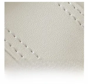 Macro shot of off-white lychee texture leather with white double stitching detail