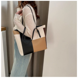 Detail of large color-block tote bag with litchi texture leather worn by a model