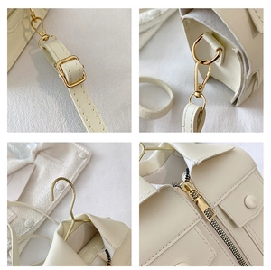 Detail of creative cream jacket-style crossbody bag with gold zippers and hardware