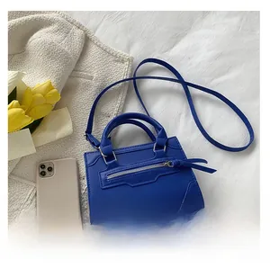 Top view of a royal blue mini leather handbag next to a smartphone for size reference